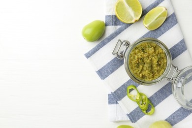 Photo of Delicious salsa sauce in jar and products on white wooden table, flat lay. Space for text