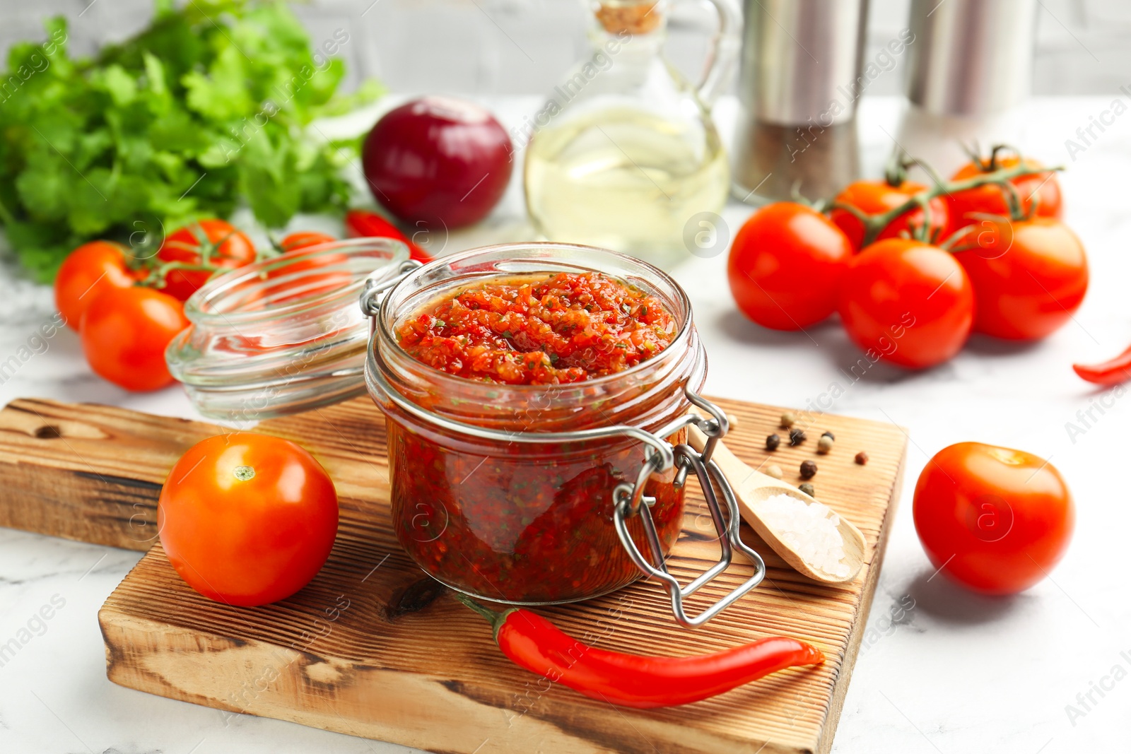 Photo of Spicy salsa and ingredients on white table