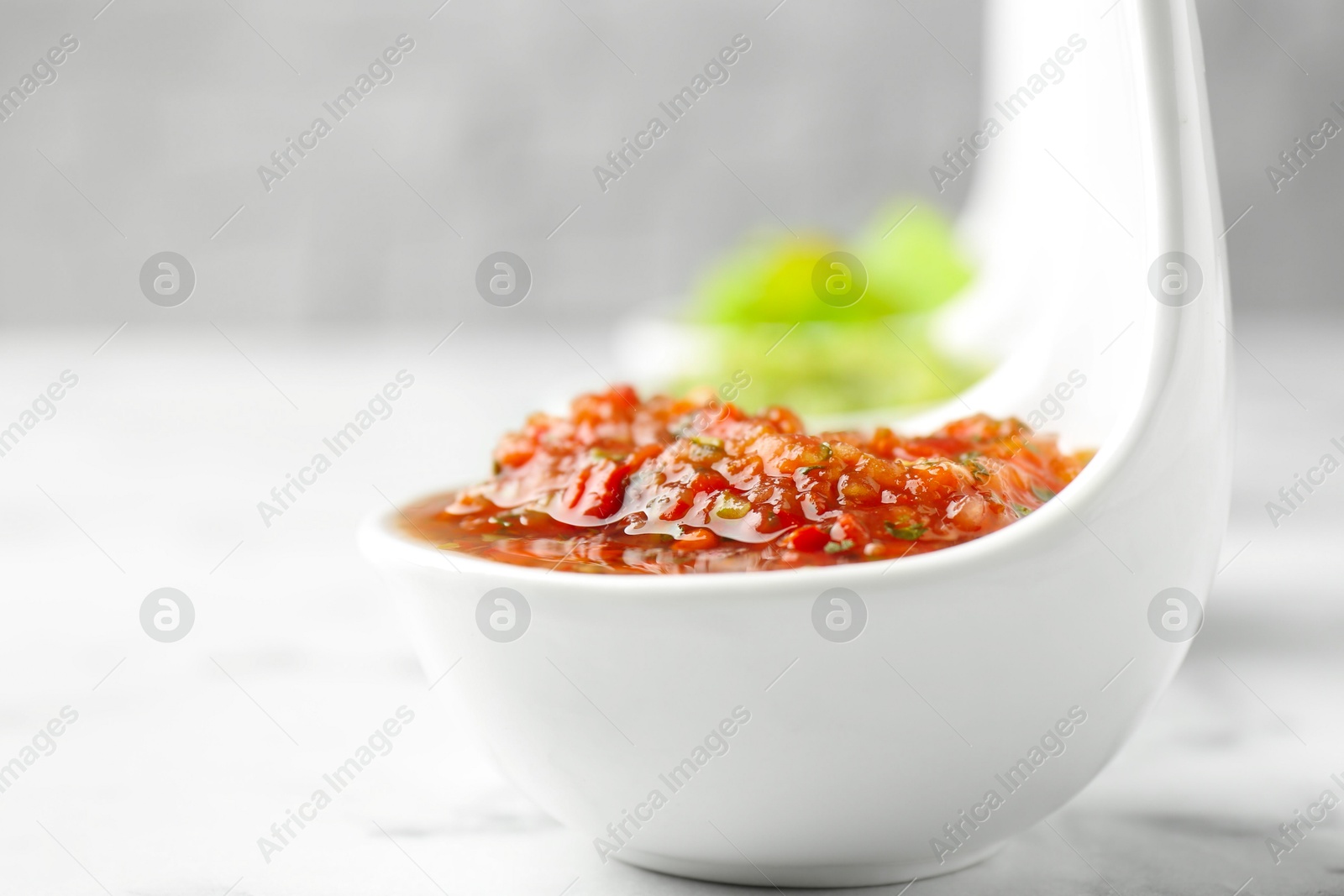 Photo of Sauce boats with salsa on white marble table, selective focus