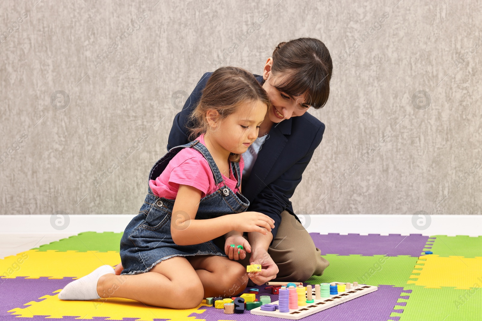 Photo of Autism therapy. Smiling psychologist and little girl playing with educational toy in mental health center