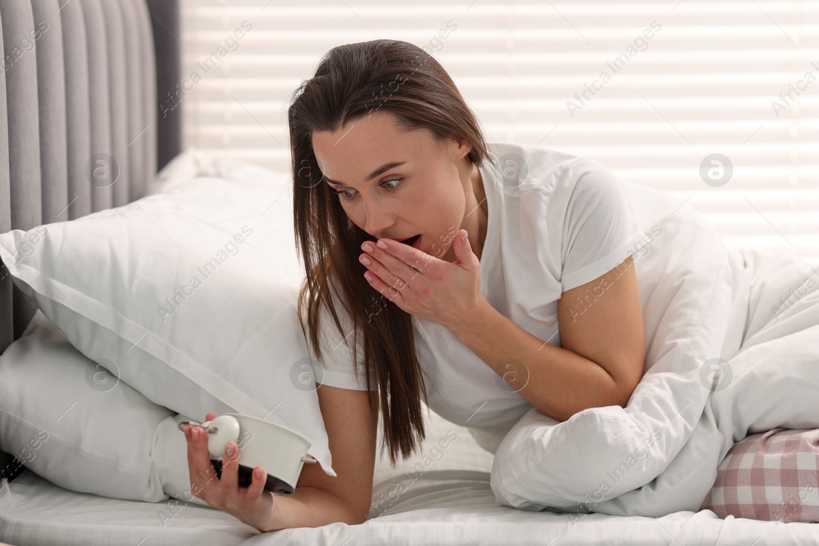 Photo of Overslept woman with alarm clock in bed at home