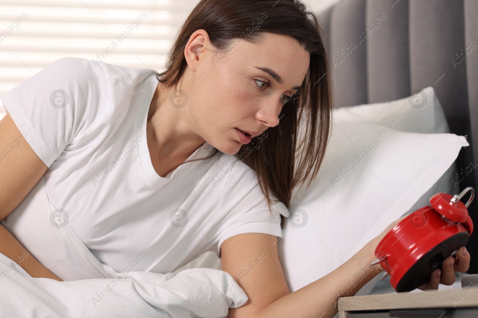 Photo of Overslept woman with alarm clock in bed at home