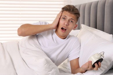 Photo of Overslept man with alarm clock in bed at home