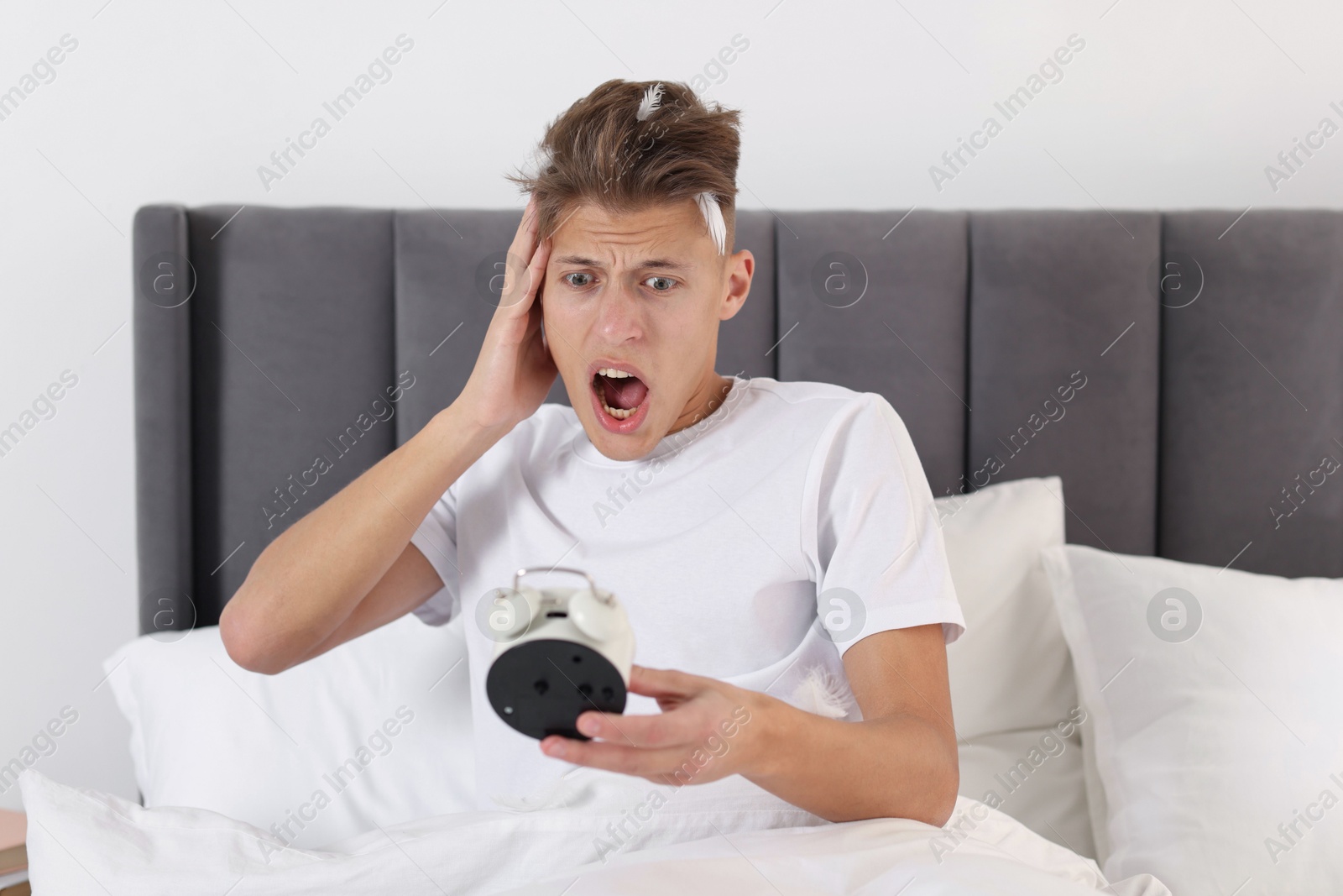 Photo of Overslept man with alarm clock in bed at home