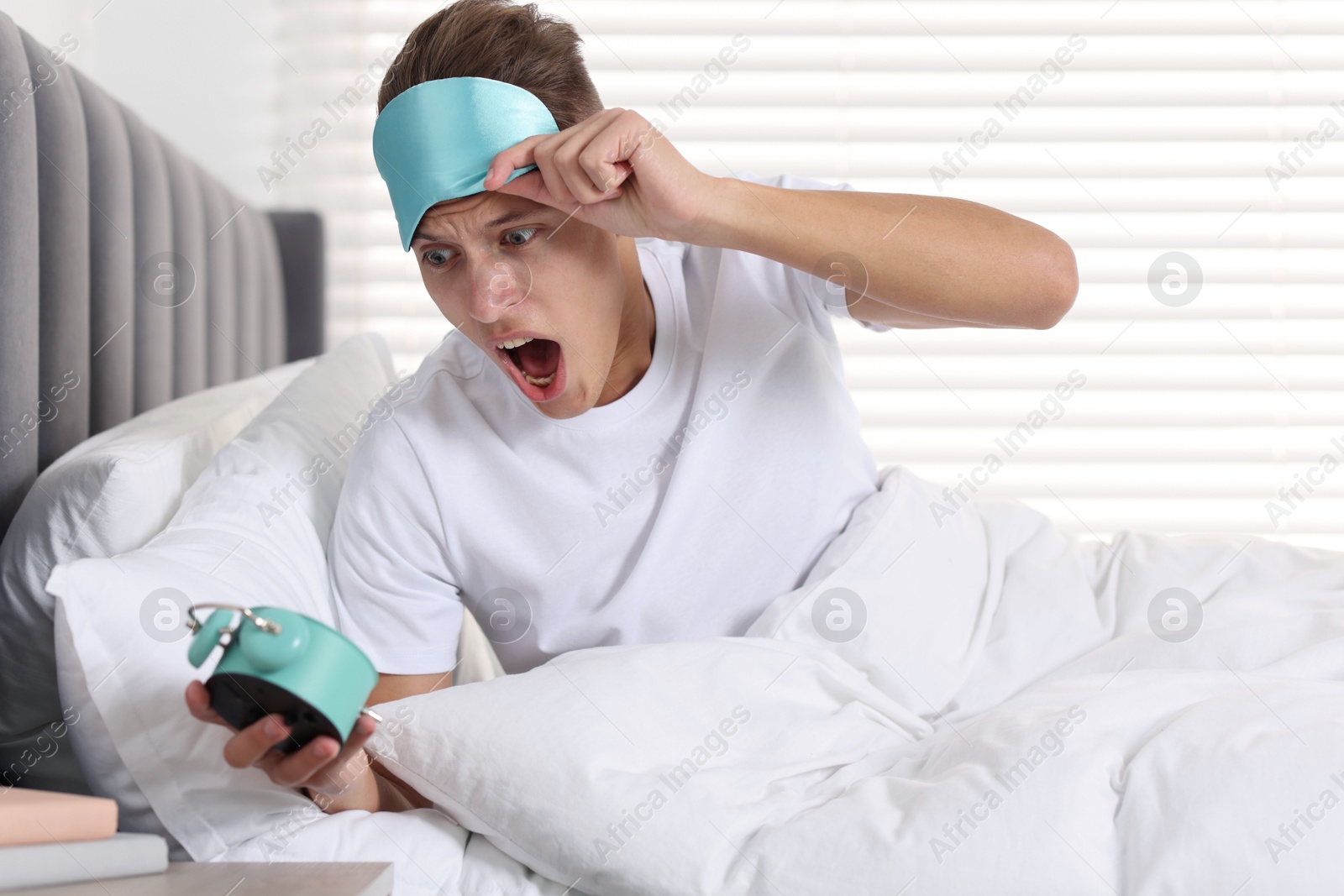 Photo of Overslept man with alarm clock in bed at home