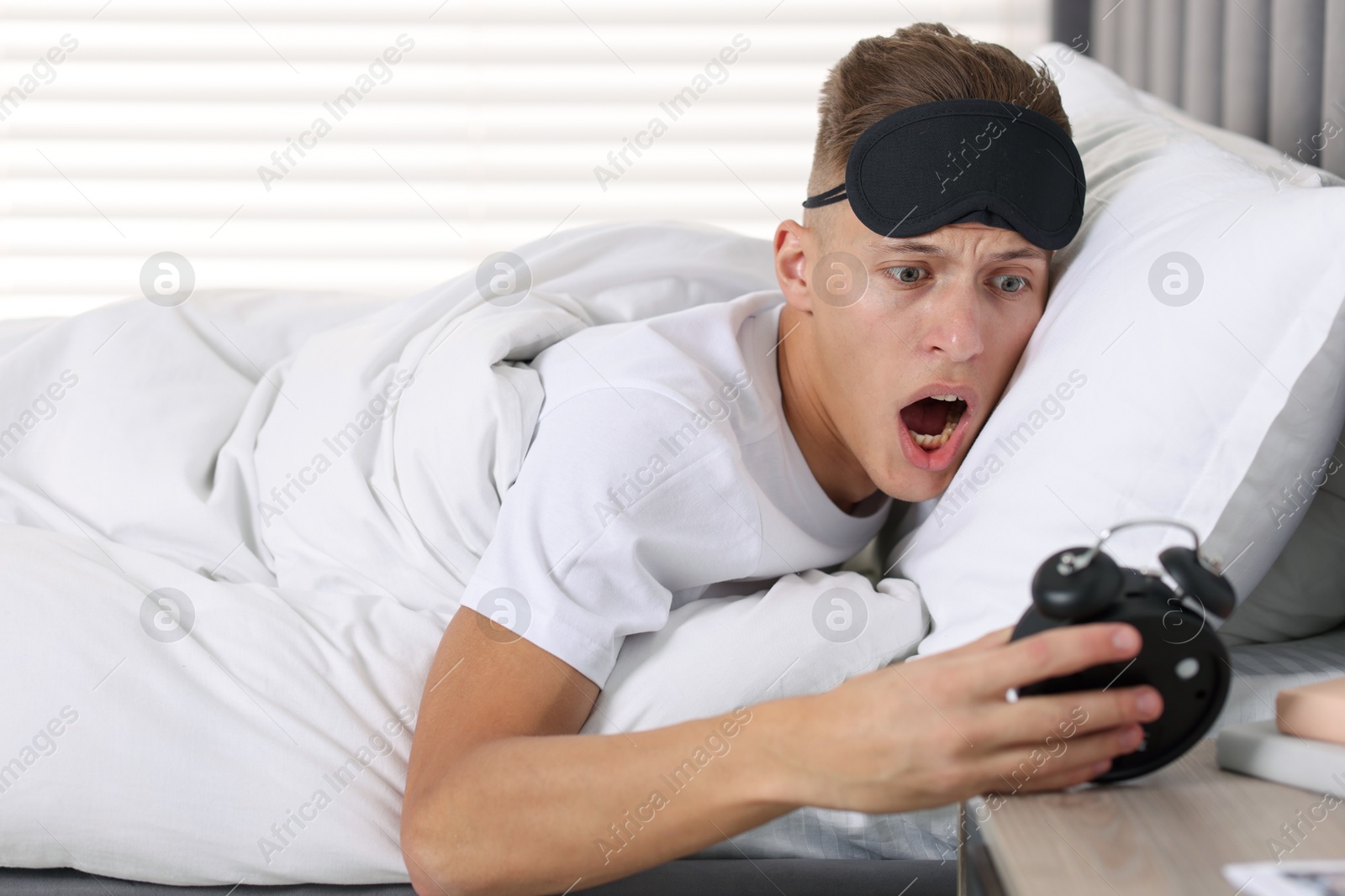 Photo of Overslept man with alarm clock in bed at home