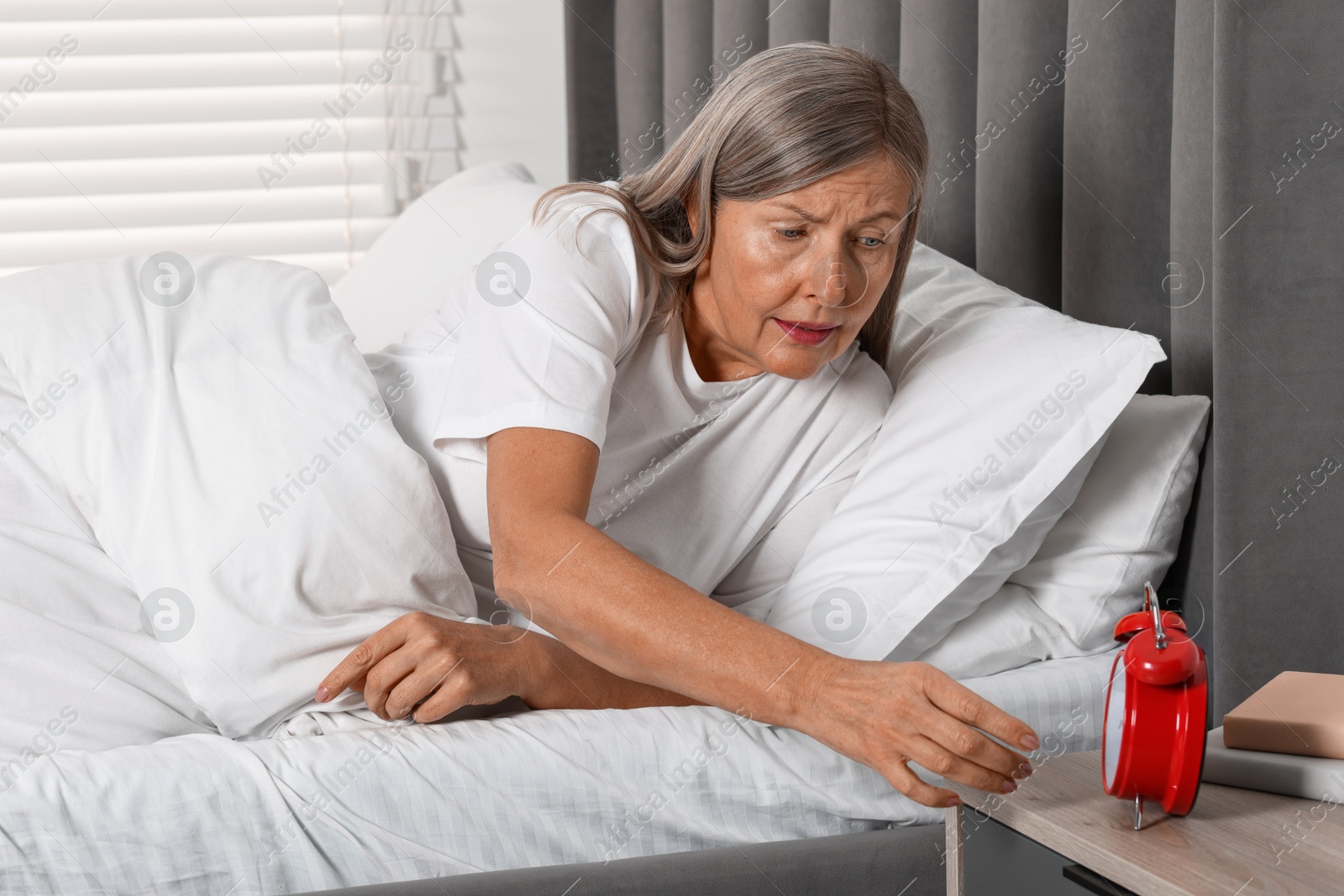 Photo of Overslept woman with alarm clock in bed at home