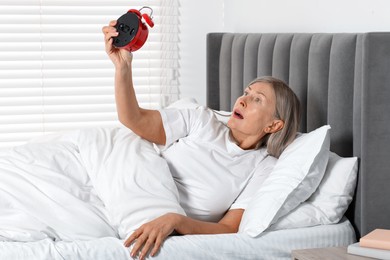 Photo of Overslept woman with alarm clock in bed at home