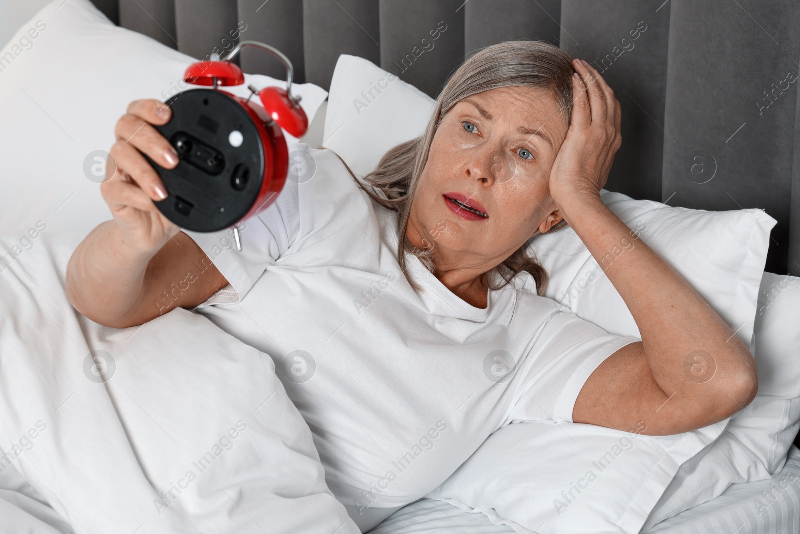 Photo of Overslept woman with alarm clock in bed at home