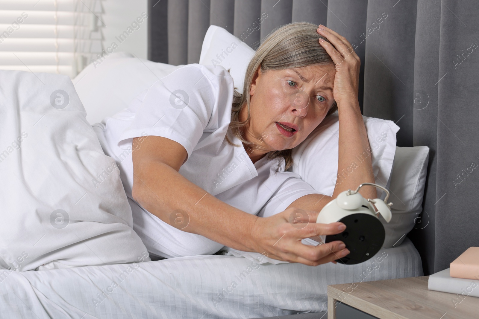 Photo of Overslept woman with alarm clock in bed at home