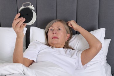 Photo of Overslept woman with alarm clock in bed at home