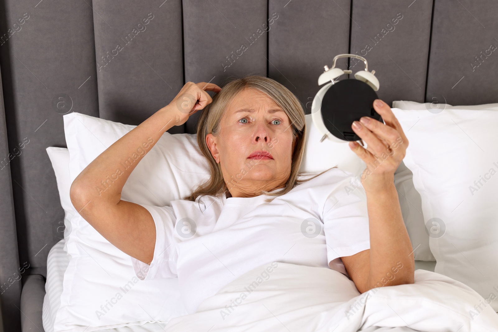 Photo of Overslept woman with alarm clock in bed at home