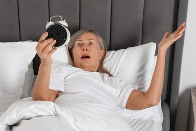 Photo of Overslept woman with alarm clock in bed at home