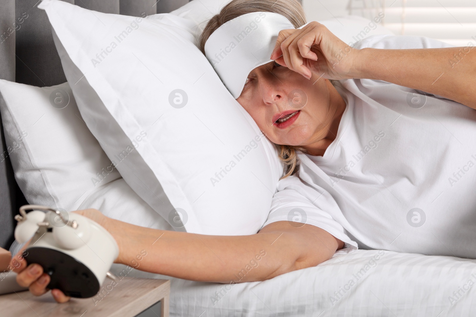 Photo of Overslept woman with alarm clock in bed at home