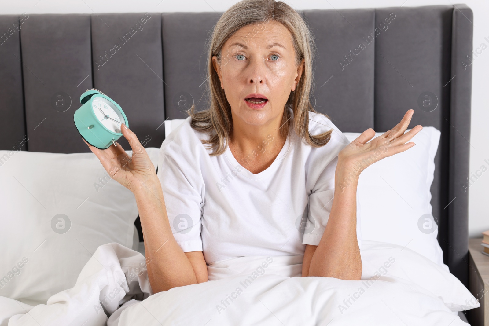 Photo of Overslept woman with alarm clock in bed at home