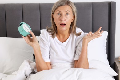 Photo of Overslept woman with alarm clock in bed at home