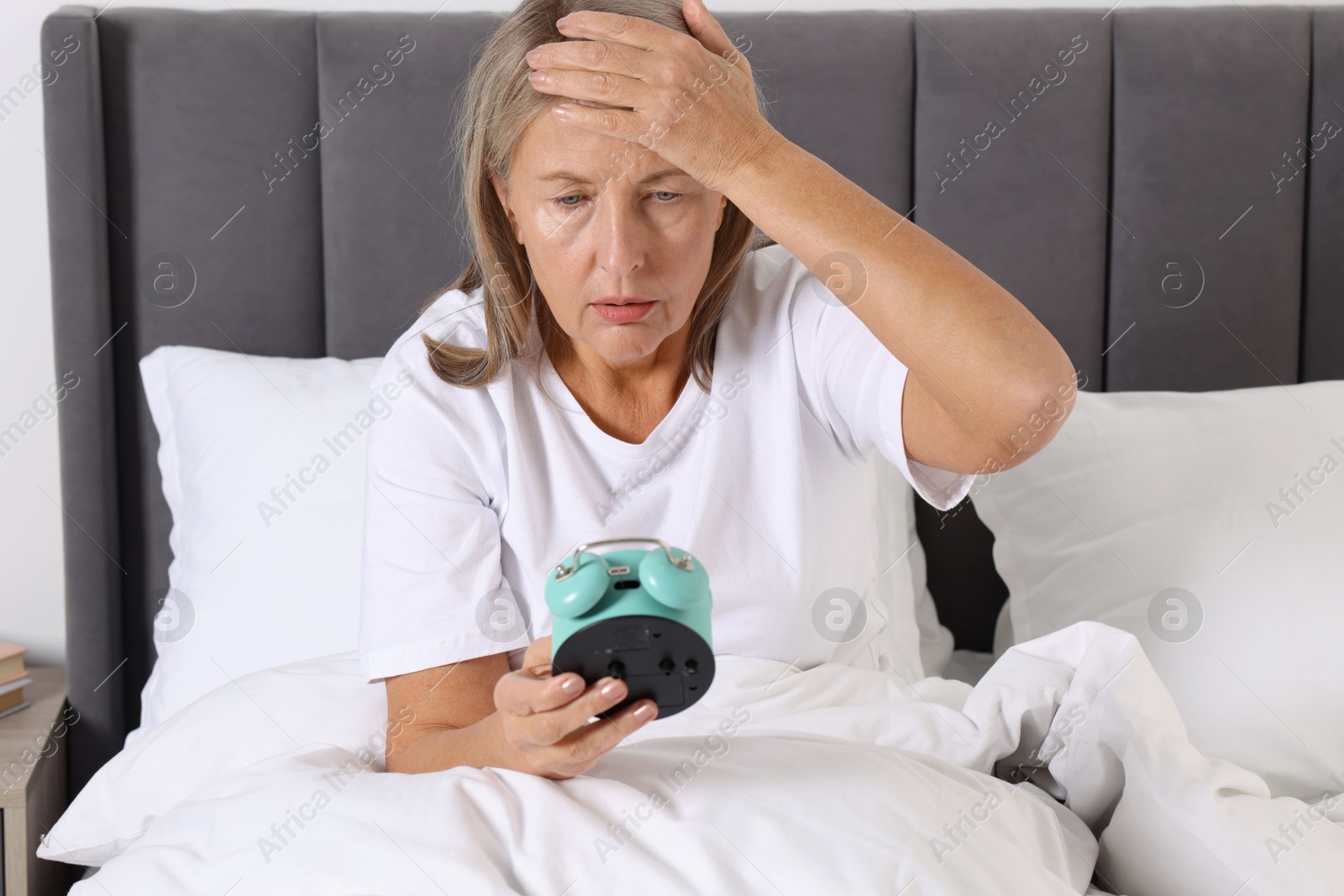 Photo of Overslept woman with alarm clock in bed at home