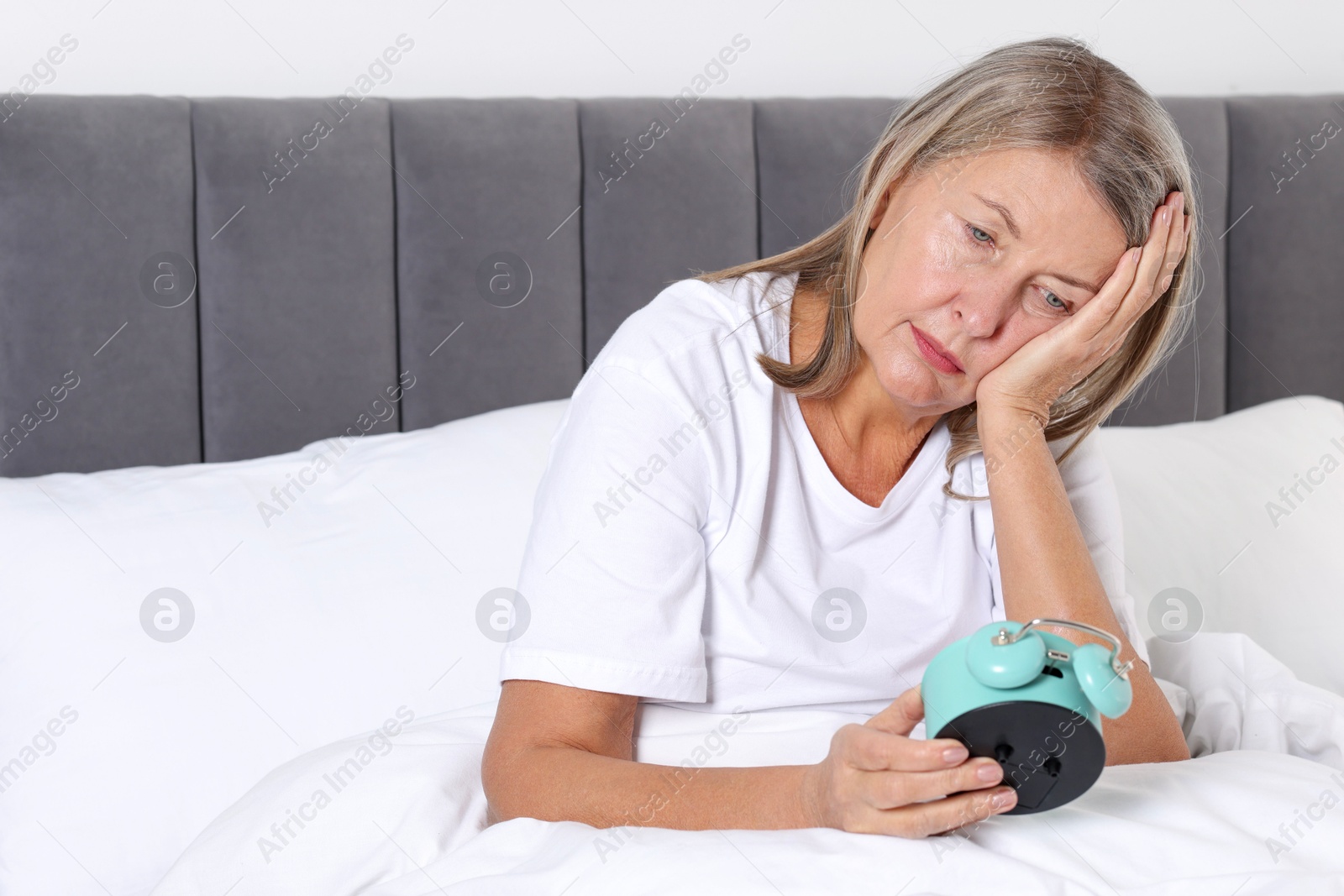 Photo of Overslept woman with alarm clock in bed at home. Space for text