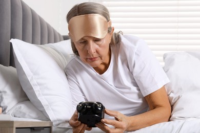 Photo of Overslept woman with alarm clock in bed at home