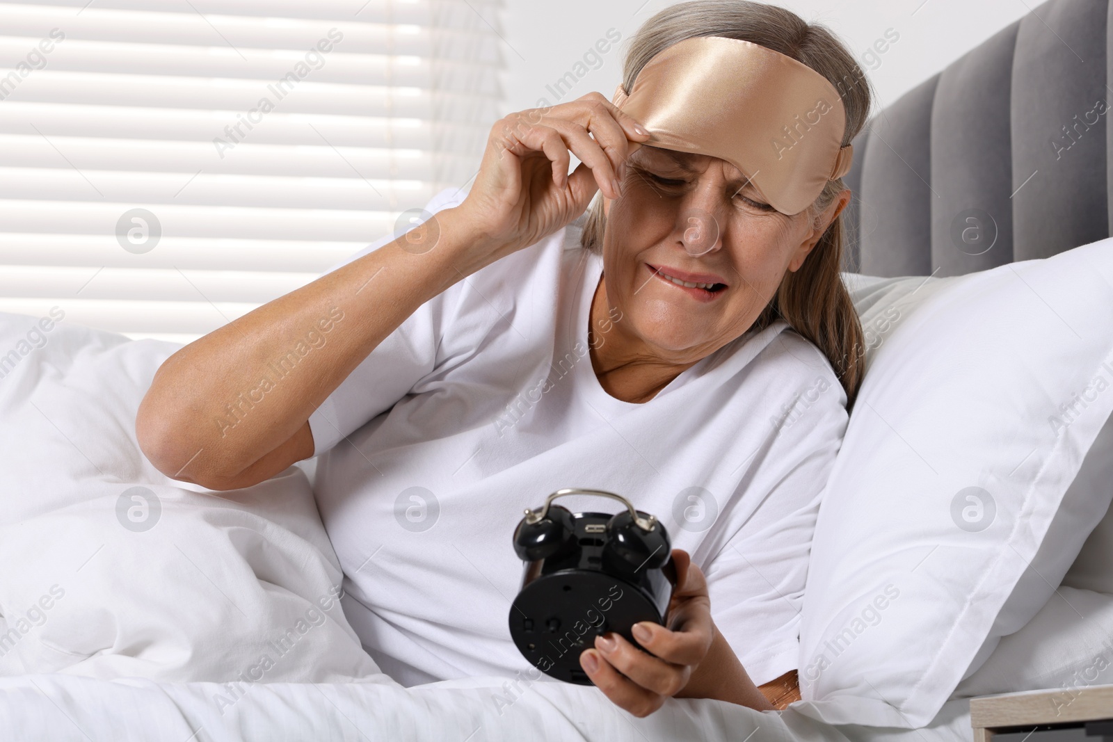 Photo of Overslept woman with alarm clock in bed at home