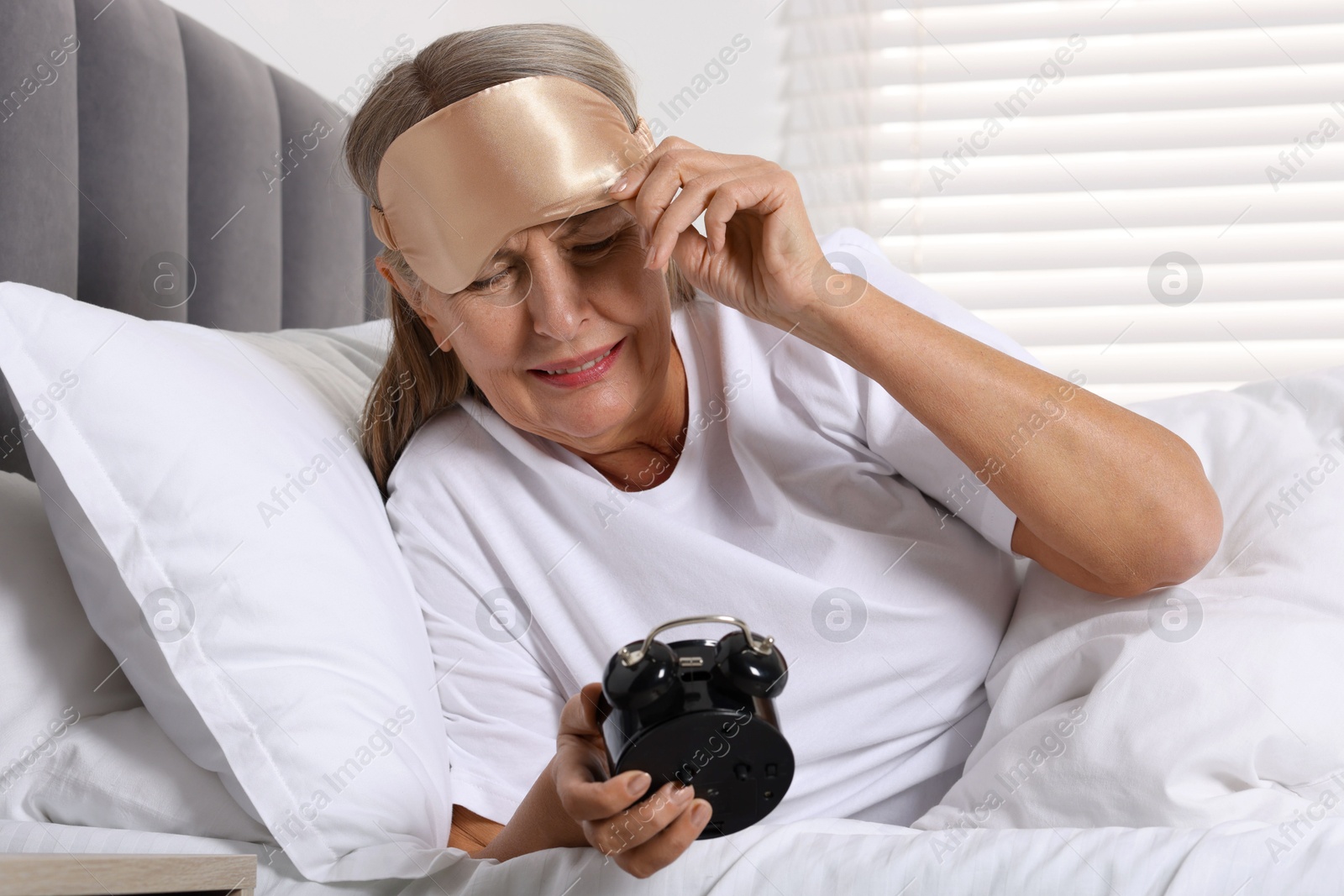 Photo of Overslept woman with alarm clock in bed at home