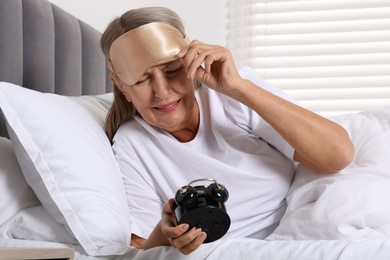 Photo of Overslept woman with alarm clock in bed at home