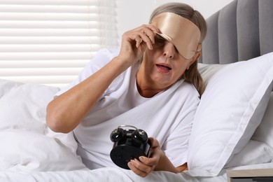 Overslept woman with alarm clock in bed at home