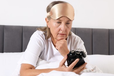 Photo of Overslept woman with alarm clock in bed at home