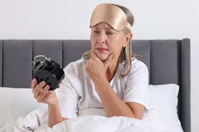 Photo of Overslept woman with alarm clock in bed at home