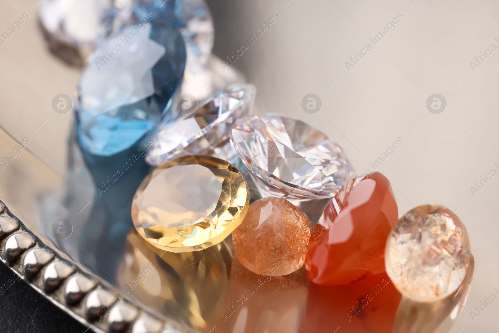 Photo of Beautiful shiny colorful gemstones on light background, closeup