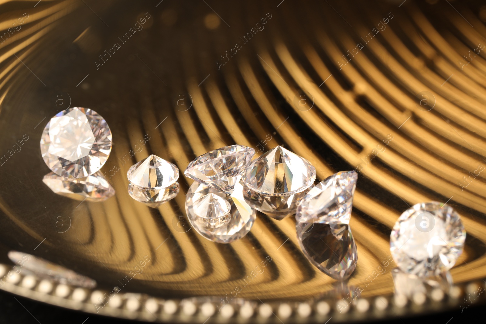 Photo of Beautiful shiny gemstones on golden tray, closeup