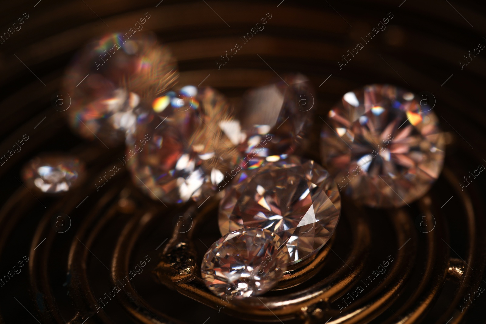 Photo of Beautiful shiny gemstones on golden tray in dark, closeup