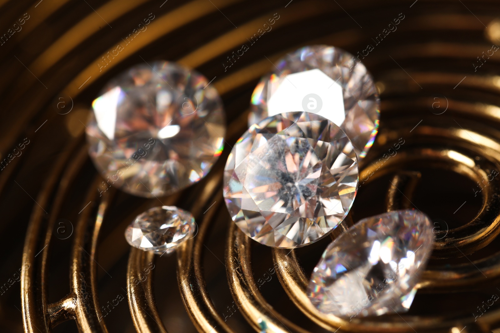 Photo of Beautiful shiny gemstones on golden tray in dark, closeup