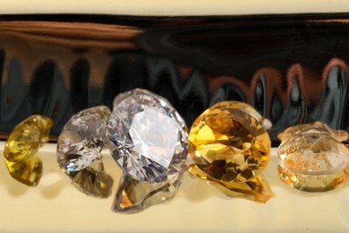 Photo of Beautiful shiny gemstones on light background, closeup