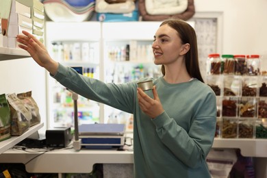 Photo of Young woman choosing food in pet shop