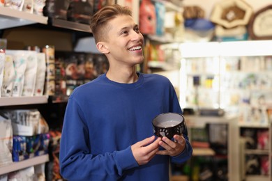 Photo of Happy man with feeding bowl in pet shop