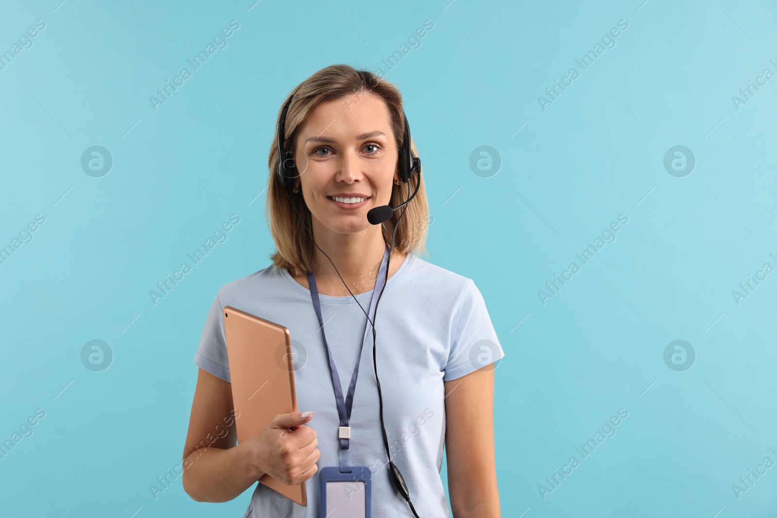 Photo of Technical support call center. Smiling operator with tablet on light blue background, space for text