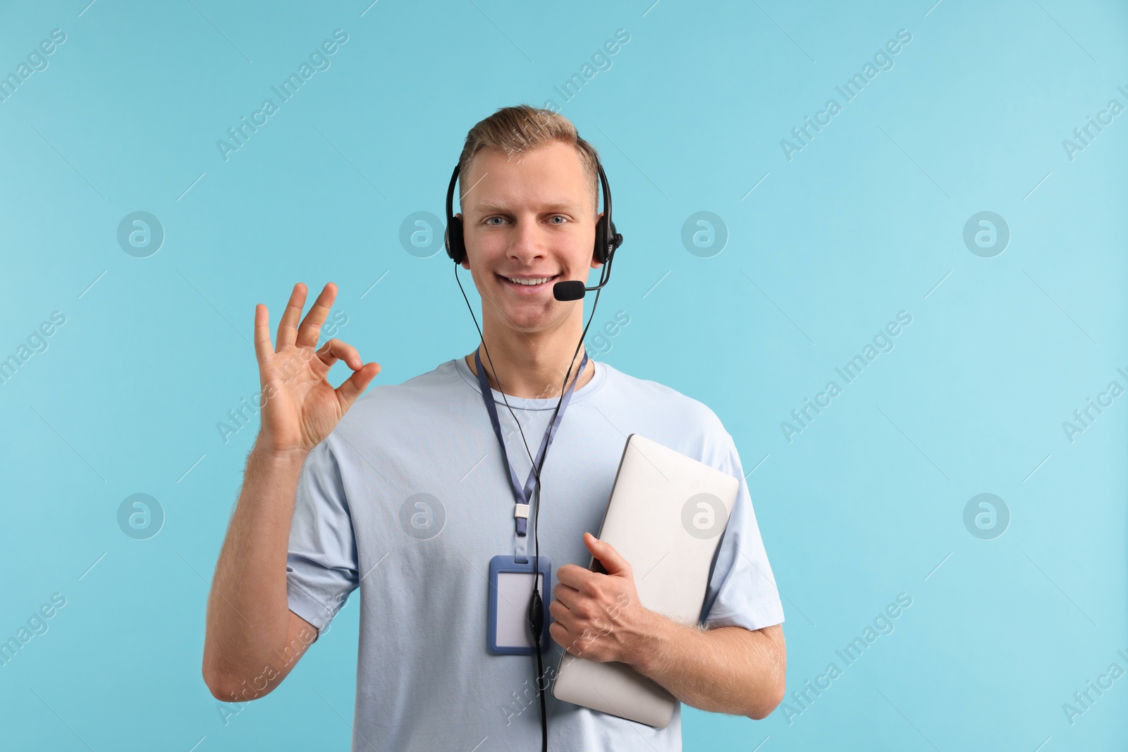 Photo of Technical support call center. Smiling operator with laptop showing ok gesture on light blue background