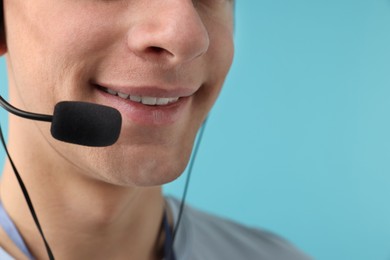 Photo of Technical support call center. Smiling operator on light blue background, closeup. Space for text