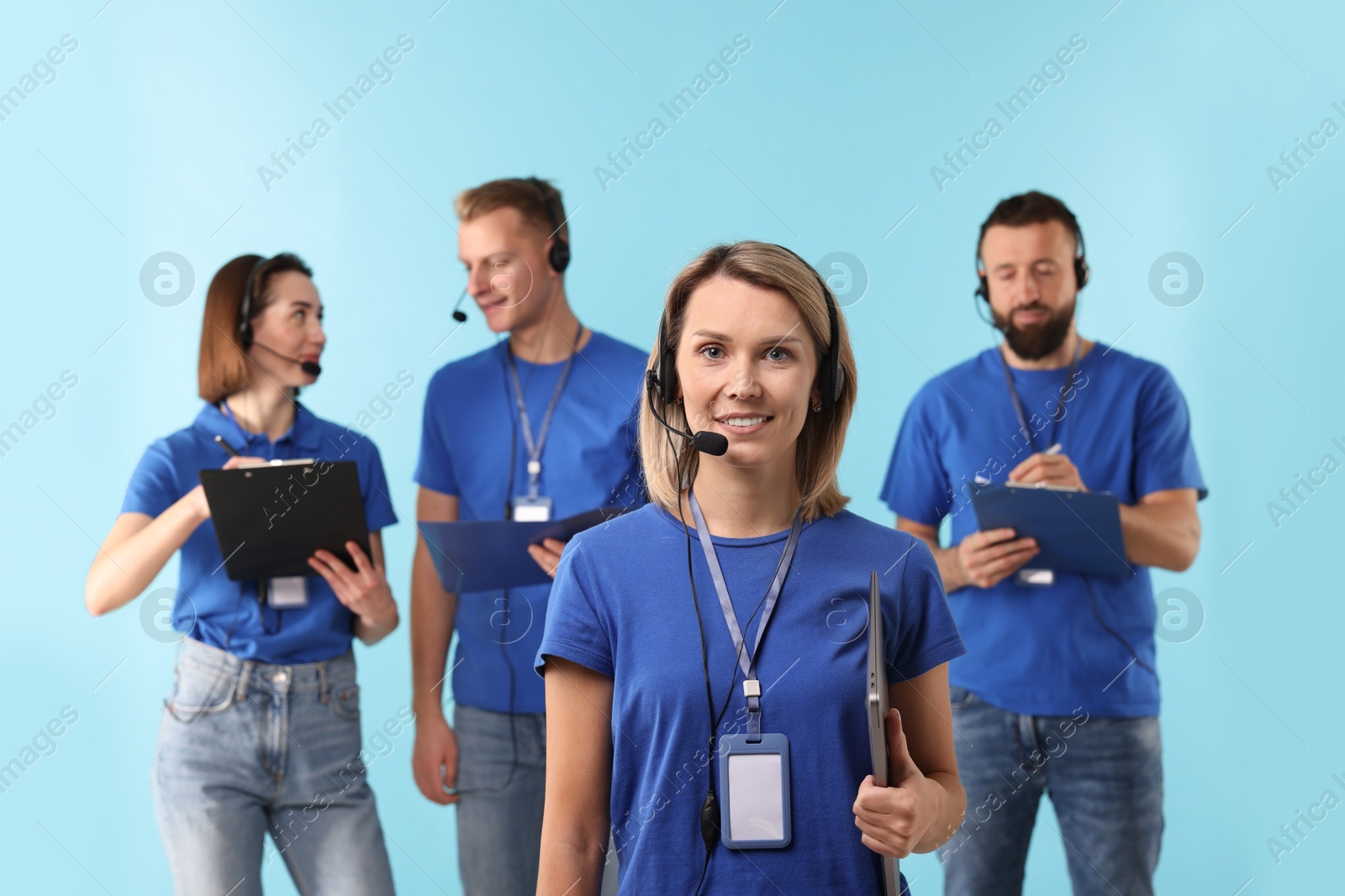 Photo of Technical support call center. Team of friendly operators working on light blue background