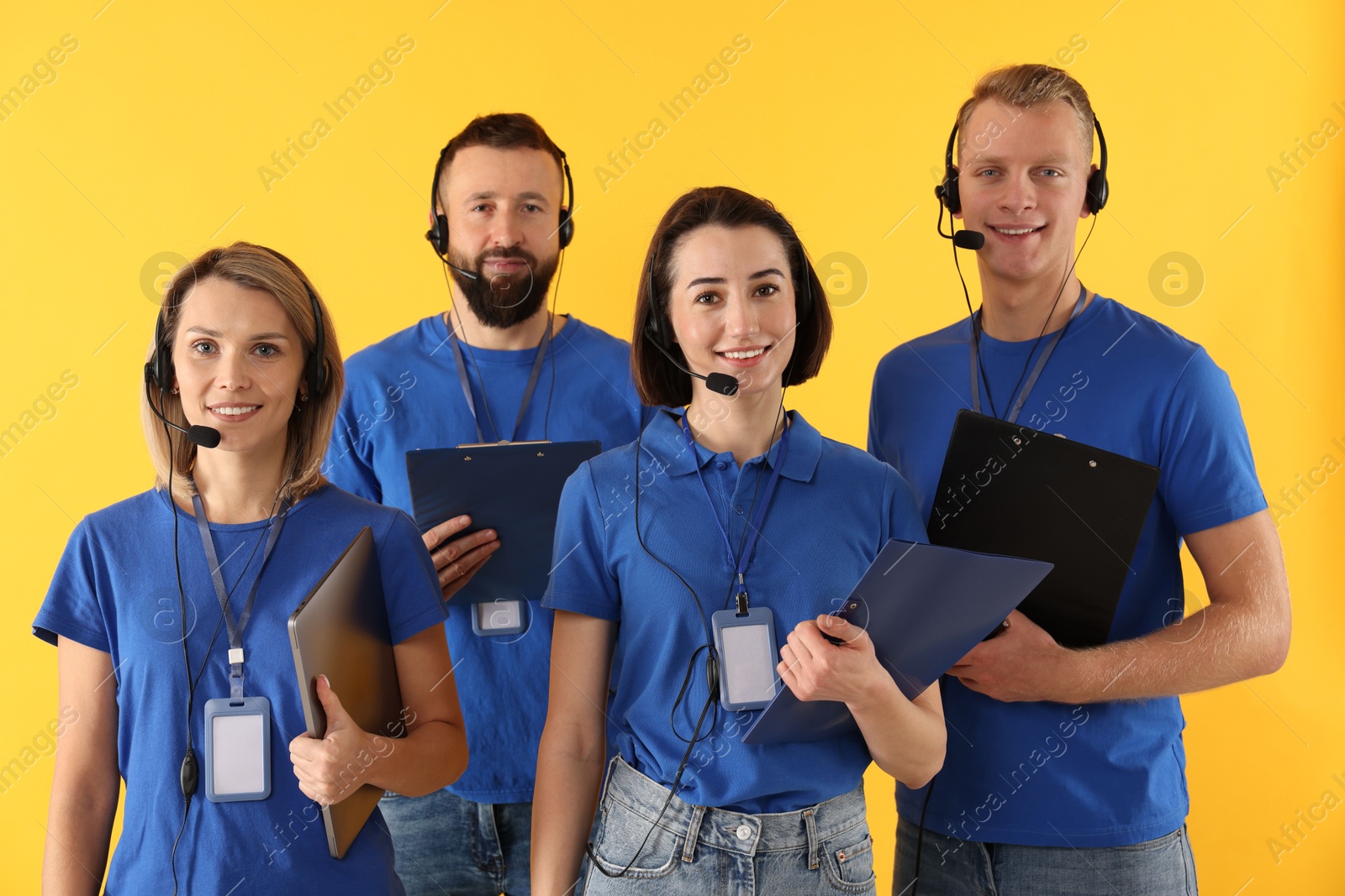 Photo of Technical support call center. Team of friendly operators on yellow background