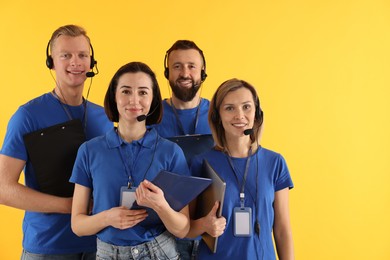 Photo of Technical support call center. Team of friendly operators on yellow background. Space for text