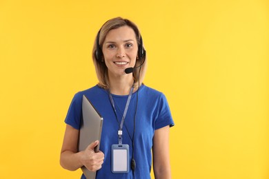 Technical support call center. Smiling operator with laptop on yellow background