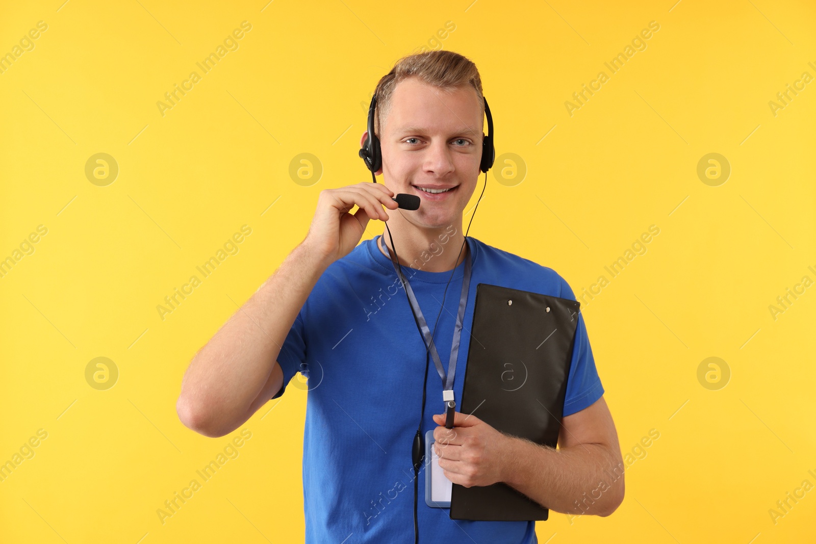 Photo of Technical support call center. Smiling operator with clipboard on yellow background