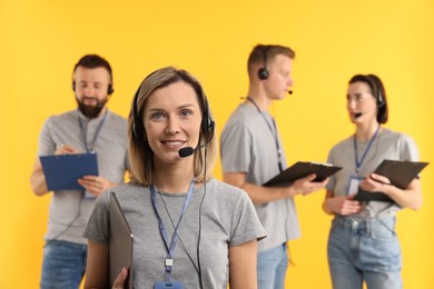 Photo of Technical support call center. Team of friendly operators on yellow background