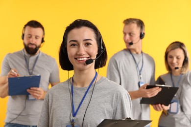 Photo of Technical support call center. Team of friendly operators on yellow background