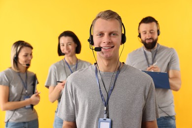 Photo of Technical support call center. Team of friendly operators on yellow background