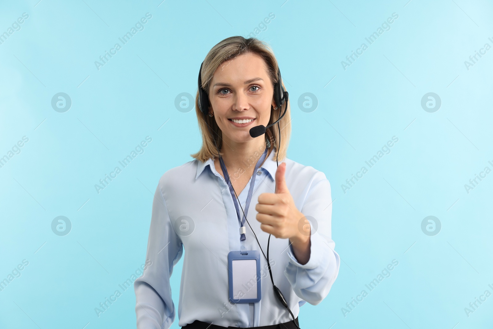 Photo of Technical support call center. Smiling operator showing thumbs up on light blue background