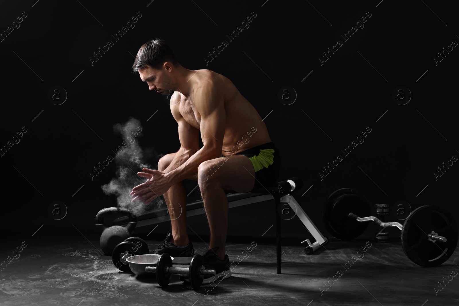 Photo of Man clapping hands with talcum powder before training on black background