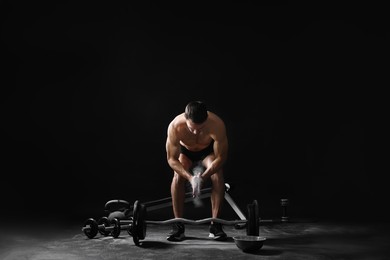 Photo of Man clapping hands with talcum powder before training with barbell on black background